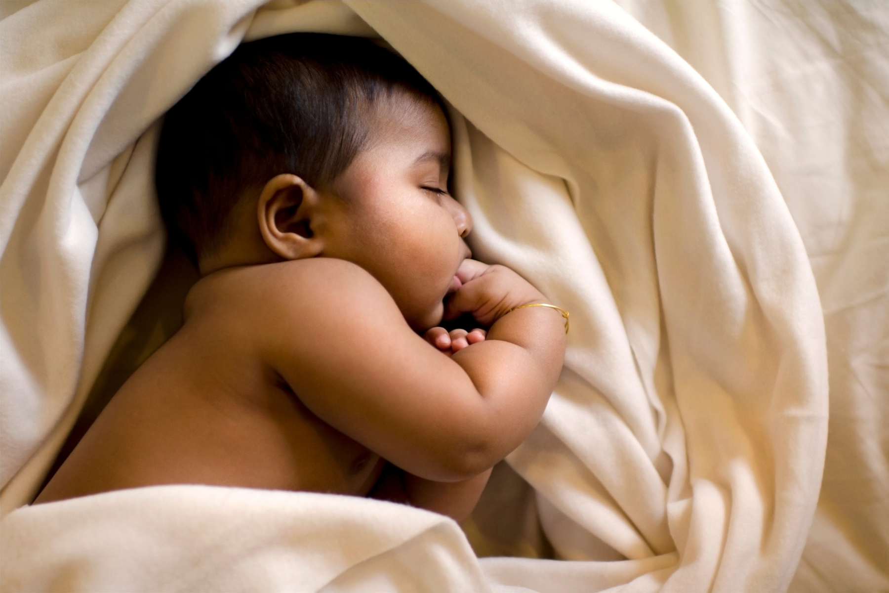 Newborn baby sleeping in soft neutral blankets